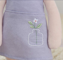 Peluche Metoo con un vestido morado.